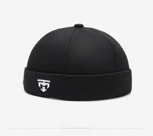 Close-up of black brimless skull cap featuring white geometric embroidery and cotton twill