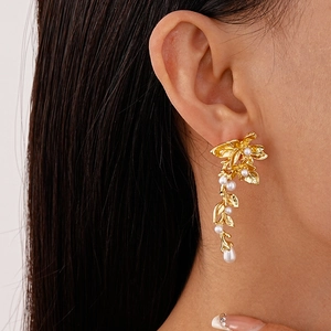Close-up of golden floral tassel earrings with pearls worn by a model in profile