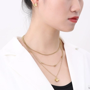 Detail of layered gold butterfly pendant necklace and matte butterfly earrings on model