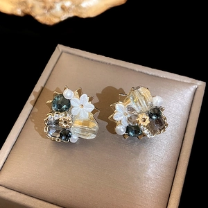 Macro shot of irregular floral earrings with crystals in a beige jewelry box