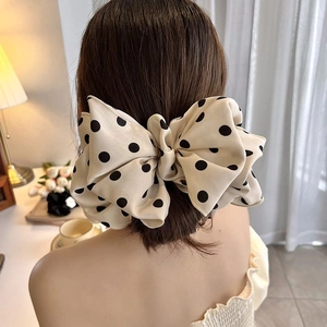 Elegant beige polka dot bow hair clip shown on model hair for a delicate spring look