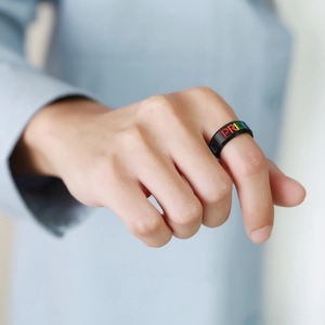 Men's black stainless steel ring with rainbow PRIDE text engraving on model's finger