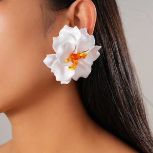 Detail of a white 3D resin flower earring with orange bead stamen worn by a model