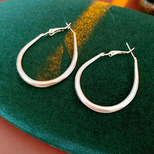 Macro detail of silver U-shaped geometric hoop earrings on green velvet surface