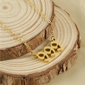 Macro shot of 999 number pendant in 18k gold finish resting on a natural wood slice
