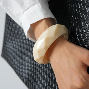Detail eines cremeweißen Acryl-Armreifs mit geometrischem Facettenschliff und modernem Design