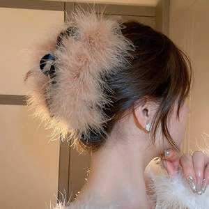 Detail of elegant large hair claw clip featuring plush apricot feathers on dark hair