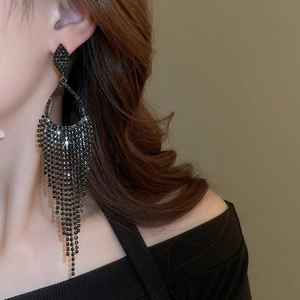 Close-up of elegant black rhinestone long tassel earrings worn by a model in a side view
