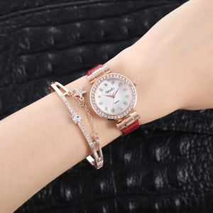 Gros plan d'une montre en or rose avec strass et bracelet étoile sur bracelet en cuir rouge