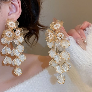 Detail of floral tassel earrings with white petals and pearls on a model wearing them
