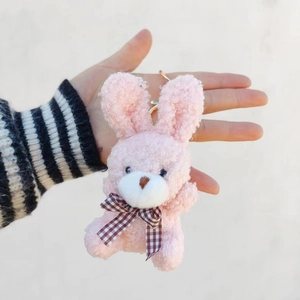 Gros plan d'un porte-clés lapin en peluche rose avec un nœud papillon et une fourrure bouclée
