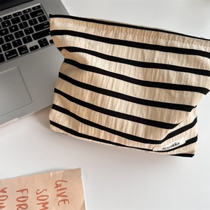 Macro detail of striped canvas makeup bag showing fabric texture and metal zipper closure
