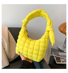 Close-up of bright yellow quilted cloud bag with unique knotted strap and zip closure