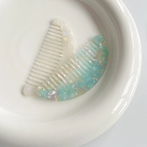 Portable acetate hair combs in pearlescent white and marble blue in a ceramic dish