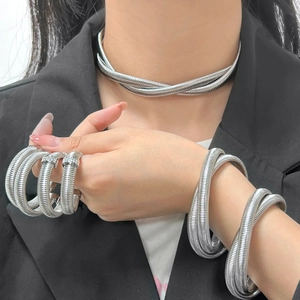 Detail showing silver snake texture metal necklace and spiral bangle on a model