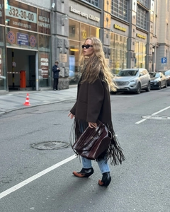 Street style shot of brown woolen coat with fringe details and crocodile pattern handbag