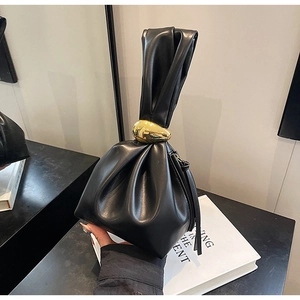 Detail of soft black leather bucket bag featuring a unique pleated handle and gold hardware