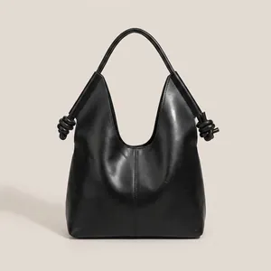 Close-up of the knot handle detail on a black minimalist leather tote shoulder bag