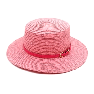 Detailed texture of pink woven boater straw hat with elegant leather strap and buckle