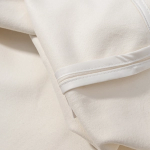 Detail aus weißem Wollstoff mit hochwertigen Kantennähten und weicher Textur