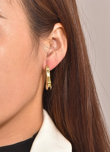 Close-up of elegant irregular long gold plated earrings worn on a female model