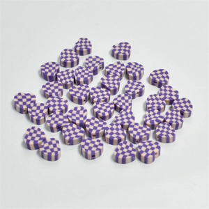 Macro shot of 10mm purple and white checkered heart clay beads for DIY jewelry making