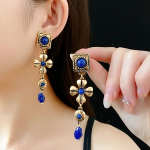 Close-up of vintage flower earrings with blue lapis stones and golden fringe on model