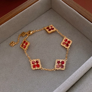 Detail view of 14K gold plated bracelet with five red diamond-shaped flower charms