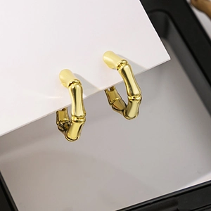 Gros plan sur des boucles d'oreilles dorées en forme de bambou sur carte blanche