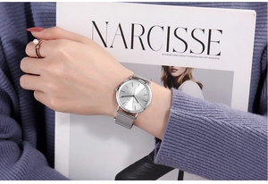 Detail of Hannah Martin silver mesh strap watch worn by a model with a fashion magazine