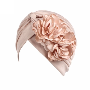 Detailed view of pink fabric turban hat featuring 3D floral decorations and pleated texture