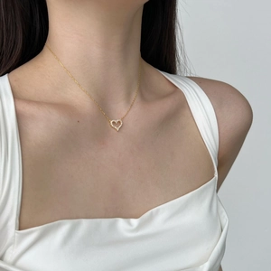 Close-up of gold heart pendant necklace with white zircons on a model's neck