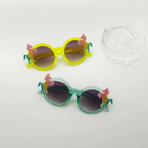Detail of yellow and mint green unicorn kids sunglasses with glitter rainbow accents