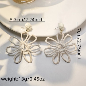 Detail view of cream white woven raffia flower earrings showing size and handmade texture