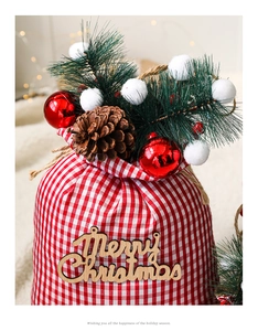 Detail of red and white plaid Christmas gift bag with wooden Merry Christmas tag