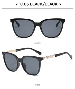 Detail of square black sunglasses featuring gold metal temples with pearl chain accents