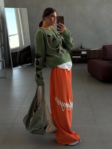 Green mushroom jacquard knit sweater and orange joggers styled with an oversized tote bag