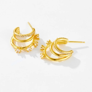 Detailed macro shot of a three-layer C-shaped gold earring with zircon stones