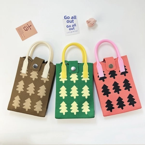 Close-up of three knitted mini bags featuring Christmas tree patterns and plastic handles