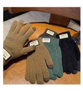 Close-up of four-color knitted touch screen gloves featuring warm labels on wooden desk