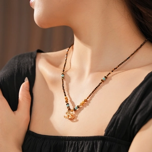 Detail of vintage necklace with tiger eye beads and golden horse pendant on neck