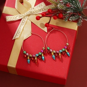 Detailed macro of gold Christmas hoop earrings featuring colorful bulb charms on a red gift box