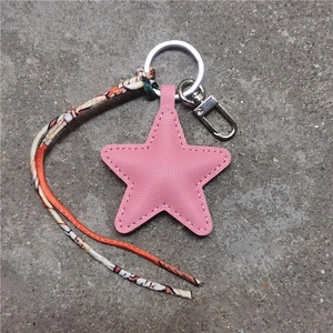 Detail van roze lederen ster sleutelhanger met zilveren ring en bedrukte lintdecoratie