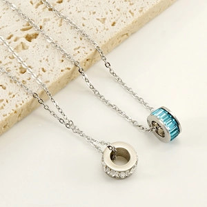 Silver stainless steel necklaces with blue and white crystal ring pendants on stone