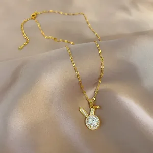 Macro view of golden rabbit pendant with zircon stones on champagne satin fabric