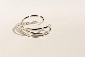 Dettaglio del bracciale rigido geometrico argento con linee incrociate e finitura lucida