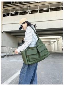 Macro detail of army green canvas crossbody bag featuring large dual flap pockets