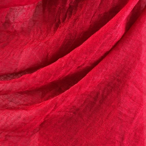 Detailed macro view of the soft crinkle texture and fringe on red cotton linen scarf