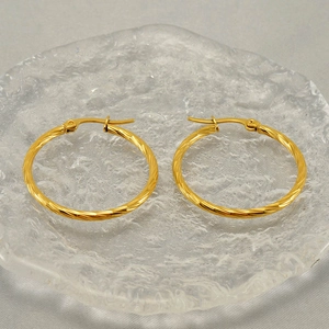 Classic gold twisted hoop earrings with spiral texture displayed on a glass tray