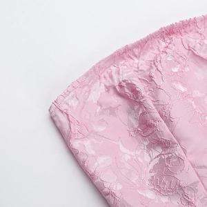 Gros plan du tissu jacquard rose à motif floral montrant la texture et l'éclat de soie